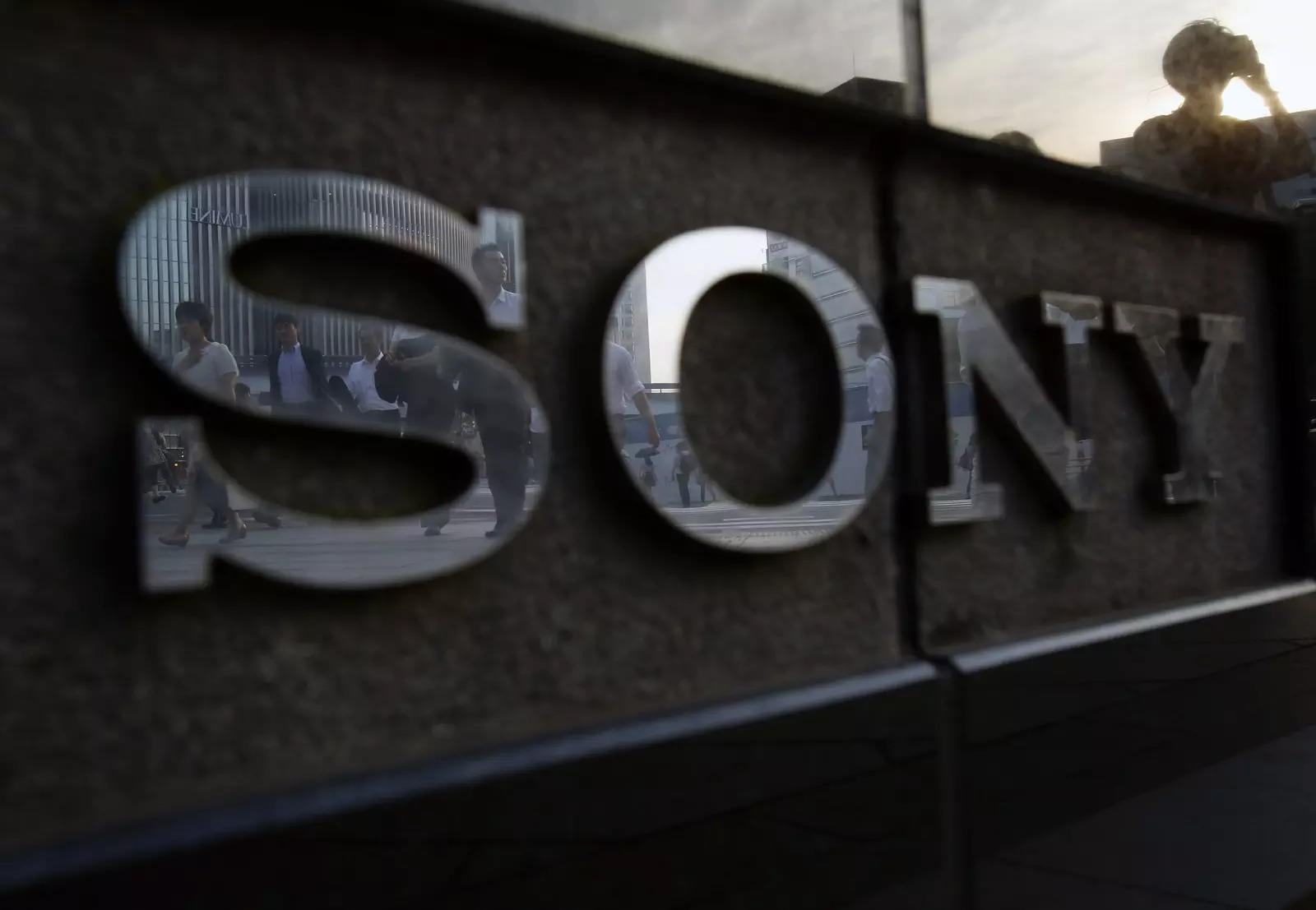 FILE PHOTO: Pedestrians are reflected in a logo of Sony Corp outside its showroom in Tokyo